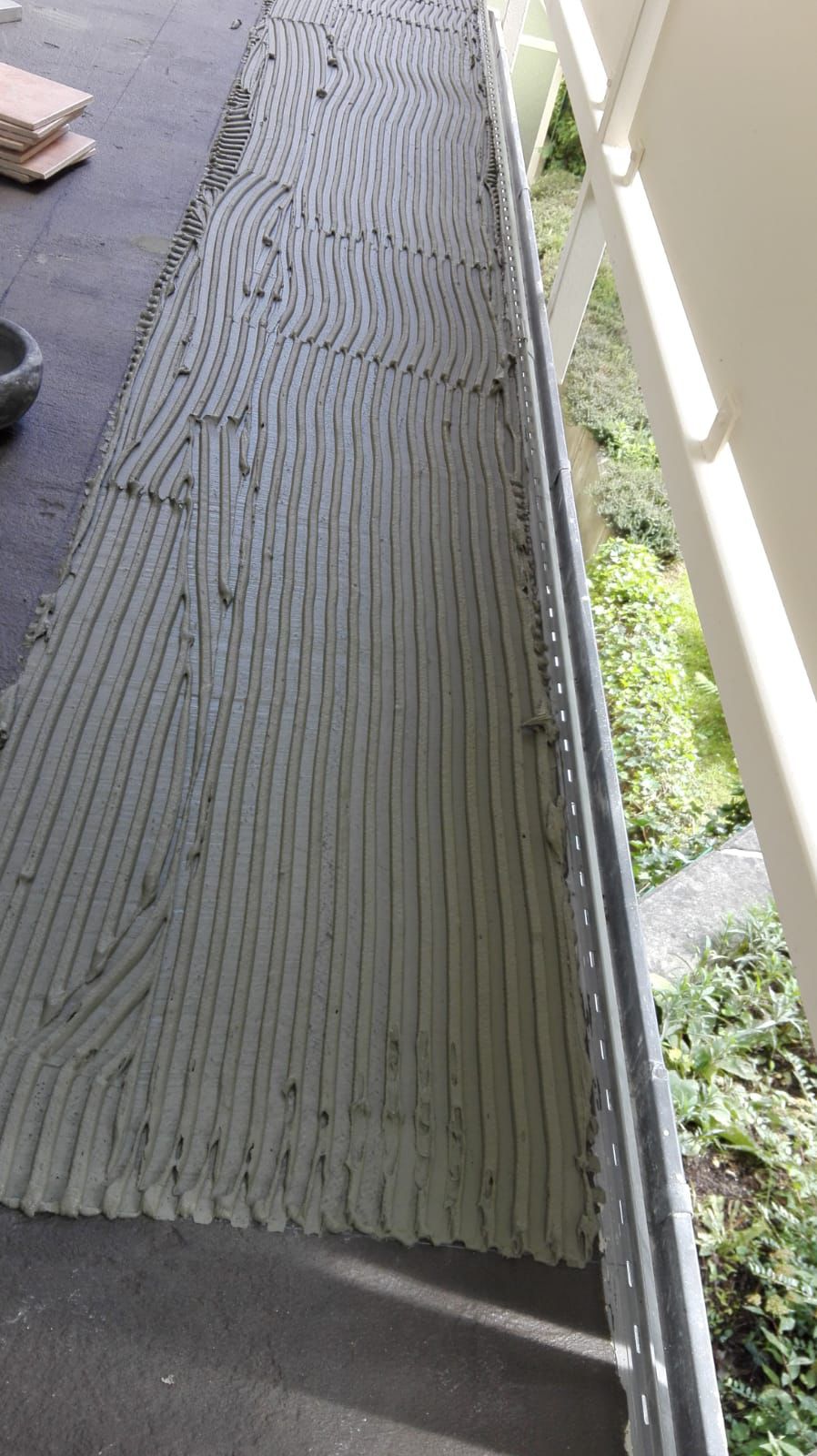 Hohlraumfreie Verklebung der Fliesen mit Kammbett entlang des Balkonprofils