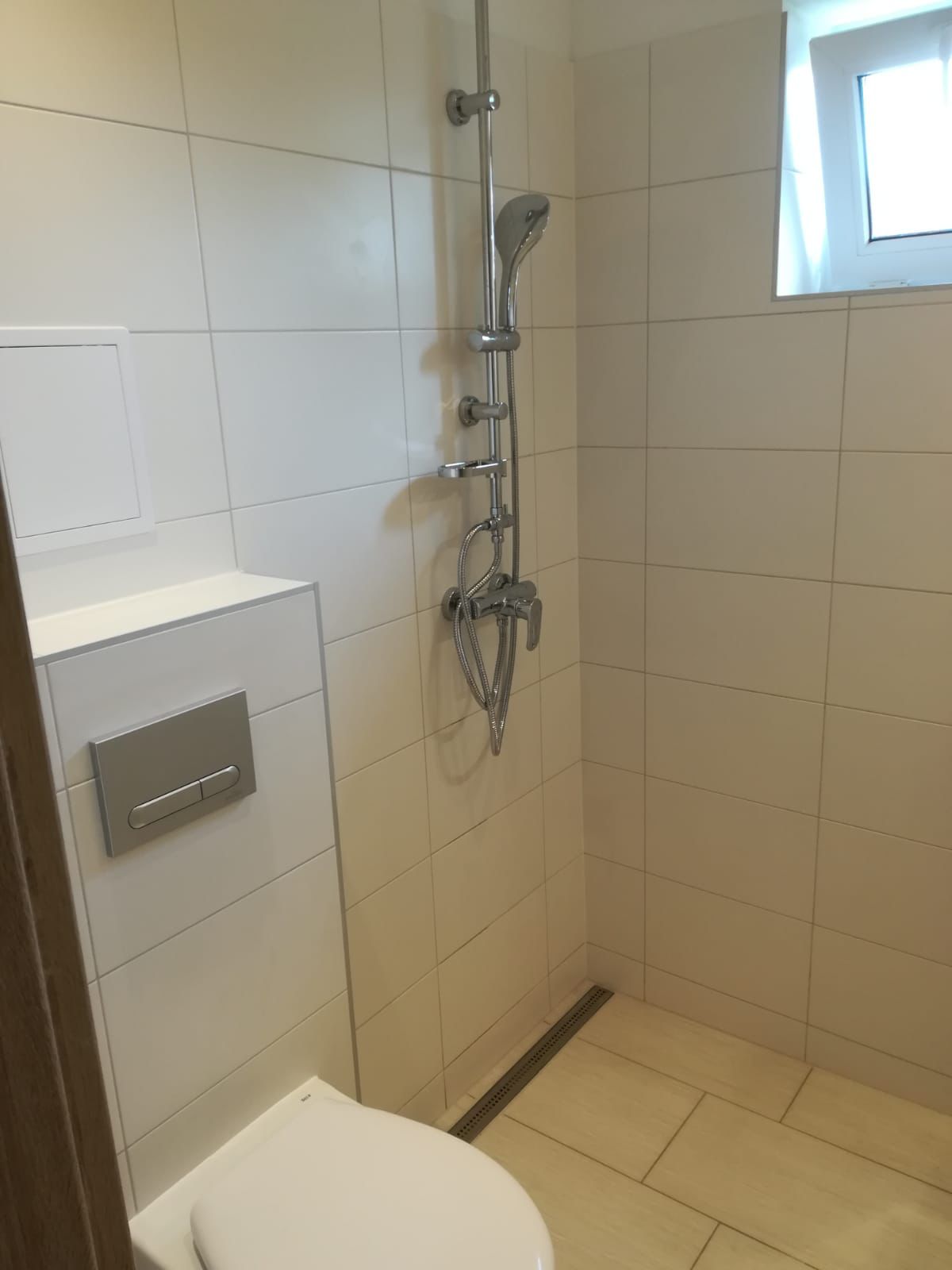 Fertig geflieste barrierearme Dusche mit Duschrinne und Armatur in Wien