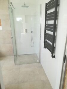 Bodengleiche begehbare Dusche mit Glastrennwand und schwarzem Heizkörper